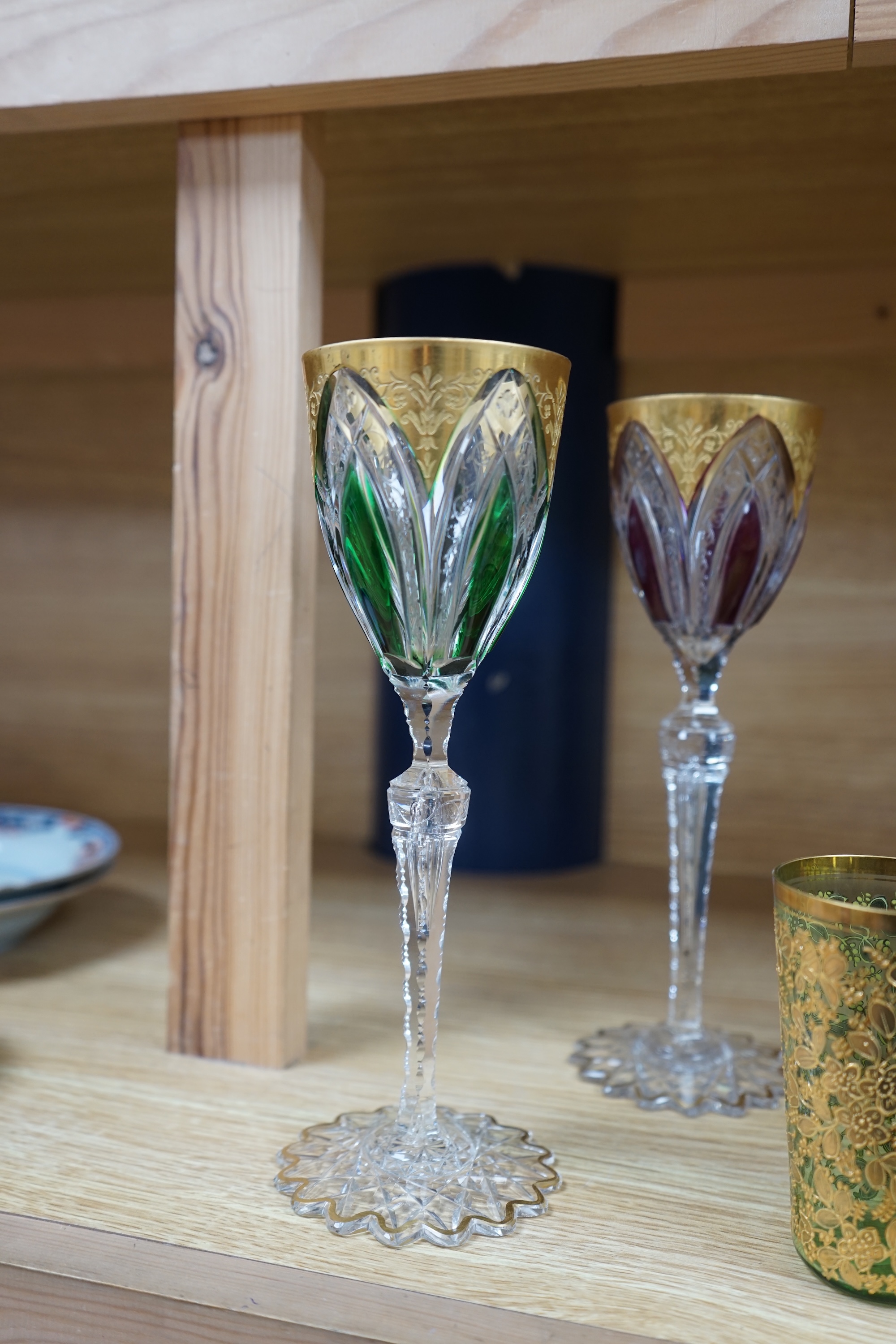 Nine Bohemian decorated glass items including a gilt rimmed and decorated glass inscribed ‘Moser 1503 D553/a’, four smaller glasses, a pair of tall stemmed glasses, 22.5cm, and two vases, tallest 19.5cm. Condition - good